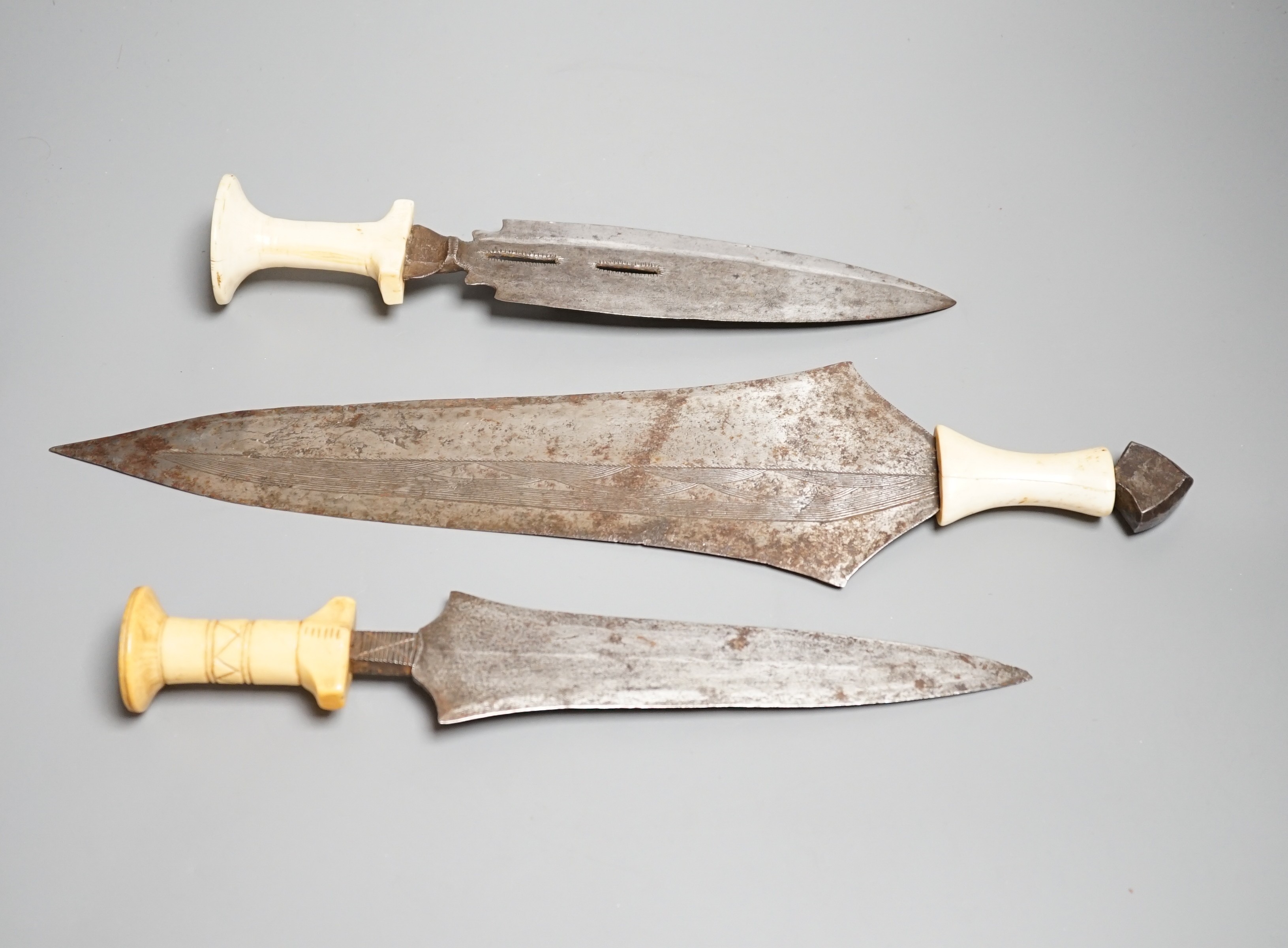 Three assorted African tribal daggers c.1900, each with ivory handle including two with decorated blades and one with iron pommel, maximum 40cms